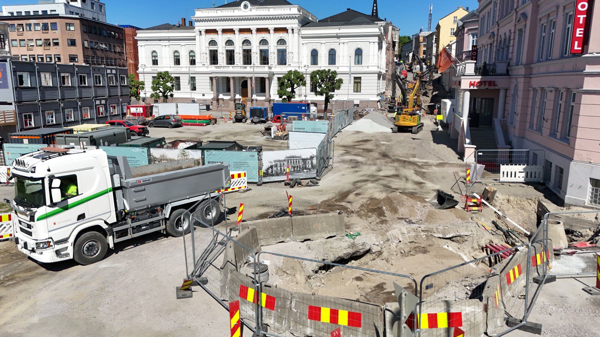 Lastebiler, gravemaskiner og containere på anleggsområdet