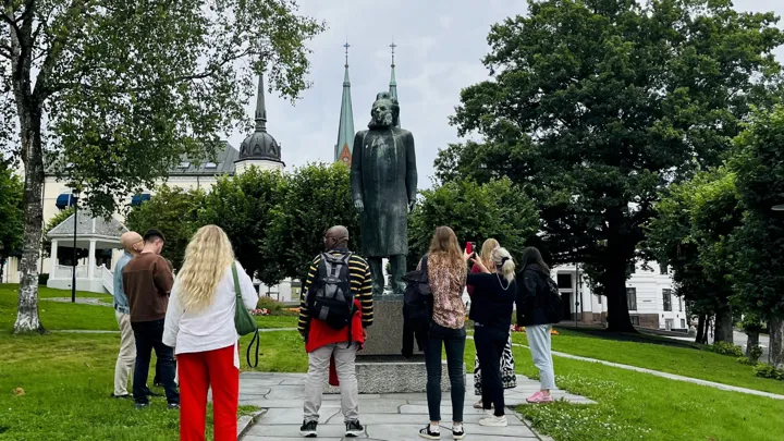 deltakerne står i Ibsenparken og ser på statuen av Henrik Ibsen.