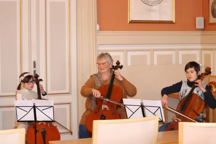 En trio med to barn og en voksen spiller cello