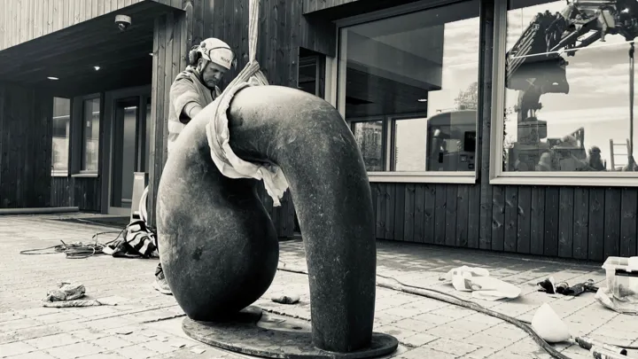 En mann monterer skulpturen.