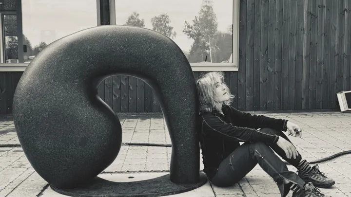 skulptur og kvinne som lener seg mot den.