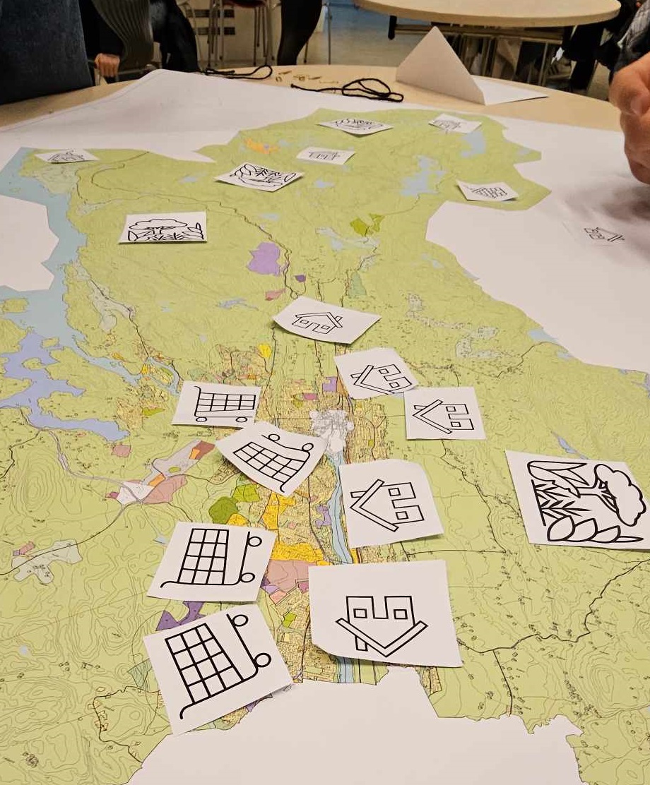 Kart med tegninger av handlevogner, boliger, natur.