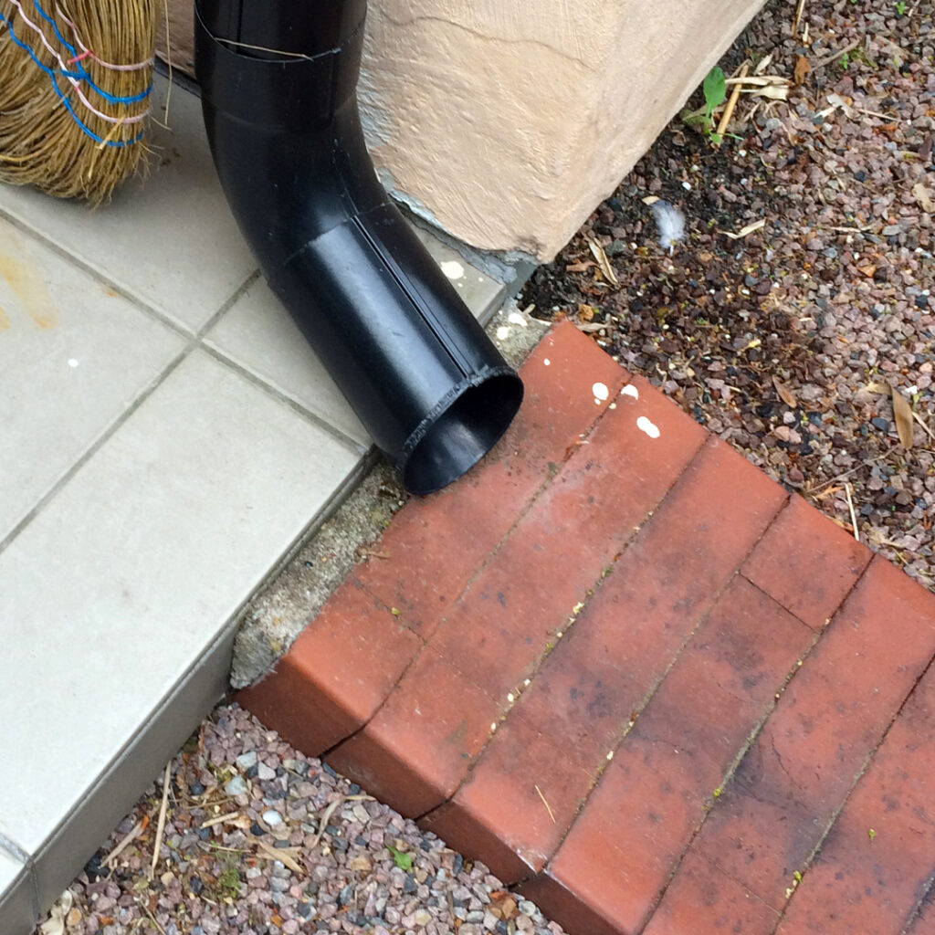 Vann fra nedløpsrøret ledes til en renne laget av murstein