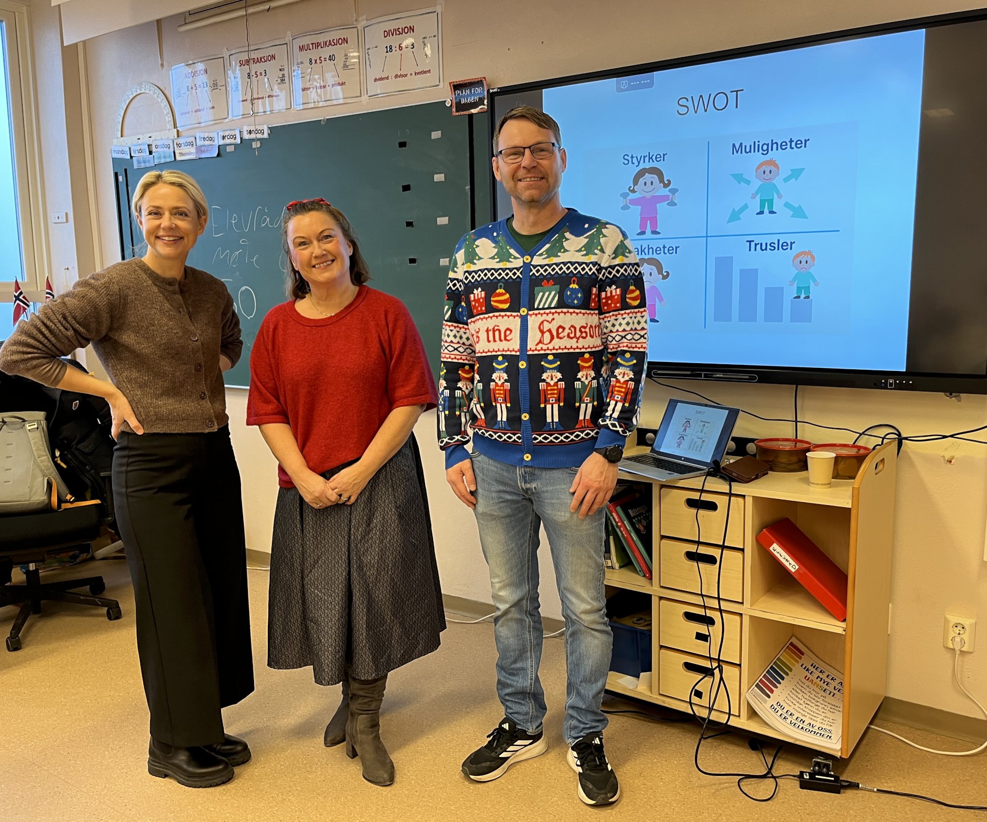 Tre lærere står i et klasserom. 