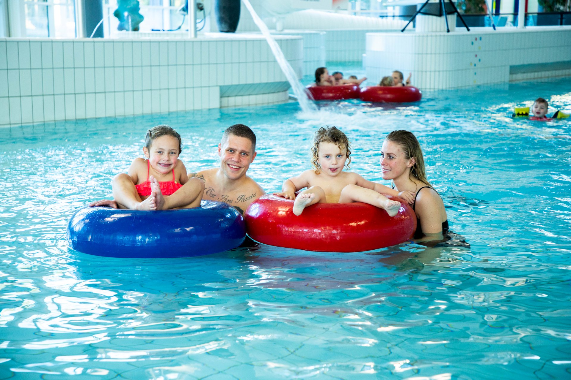 Mor og far bader i svømmebasseng med to barn.