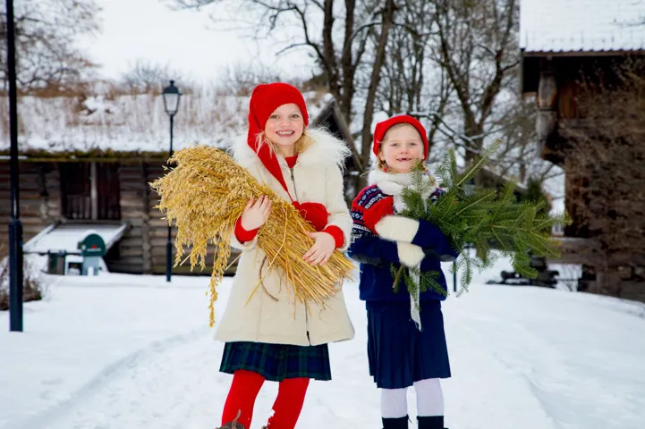 To barn i nisseklær som holder julepynt