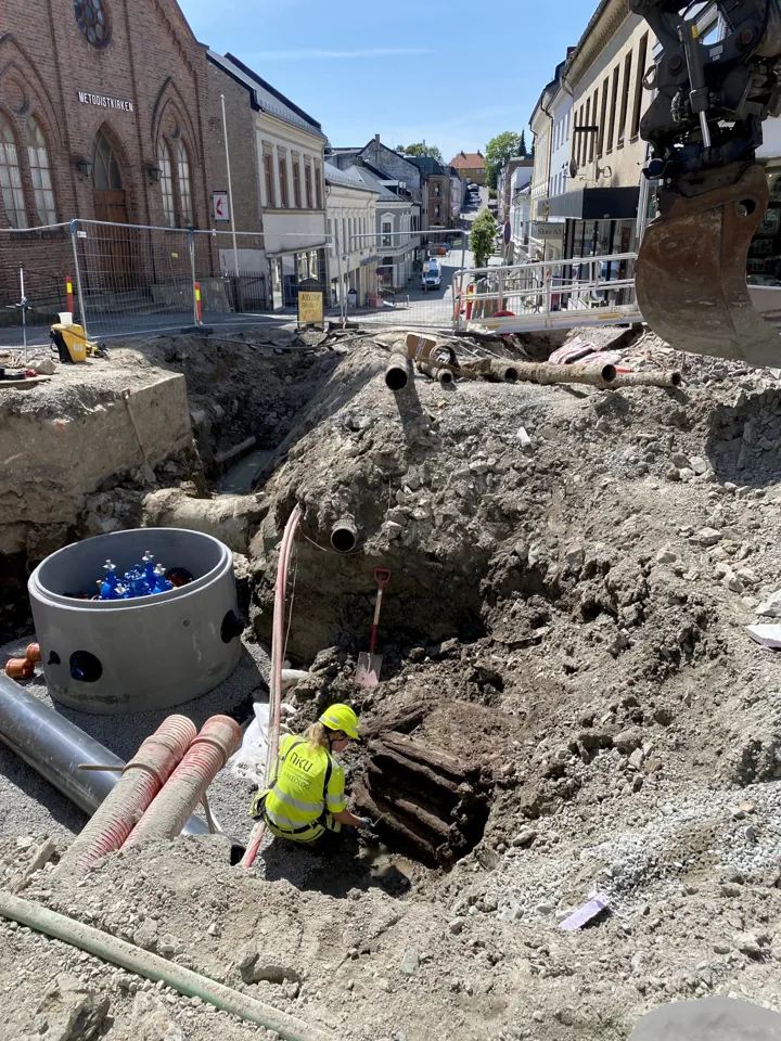 Arkeolog fra NIKU graver frem brønnen i grøfta hvor den ble funnet.