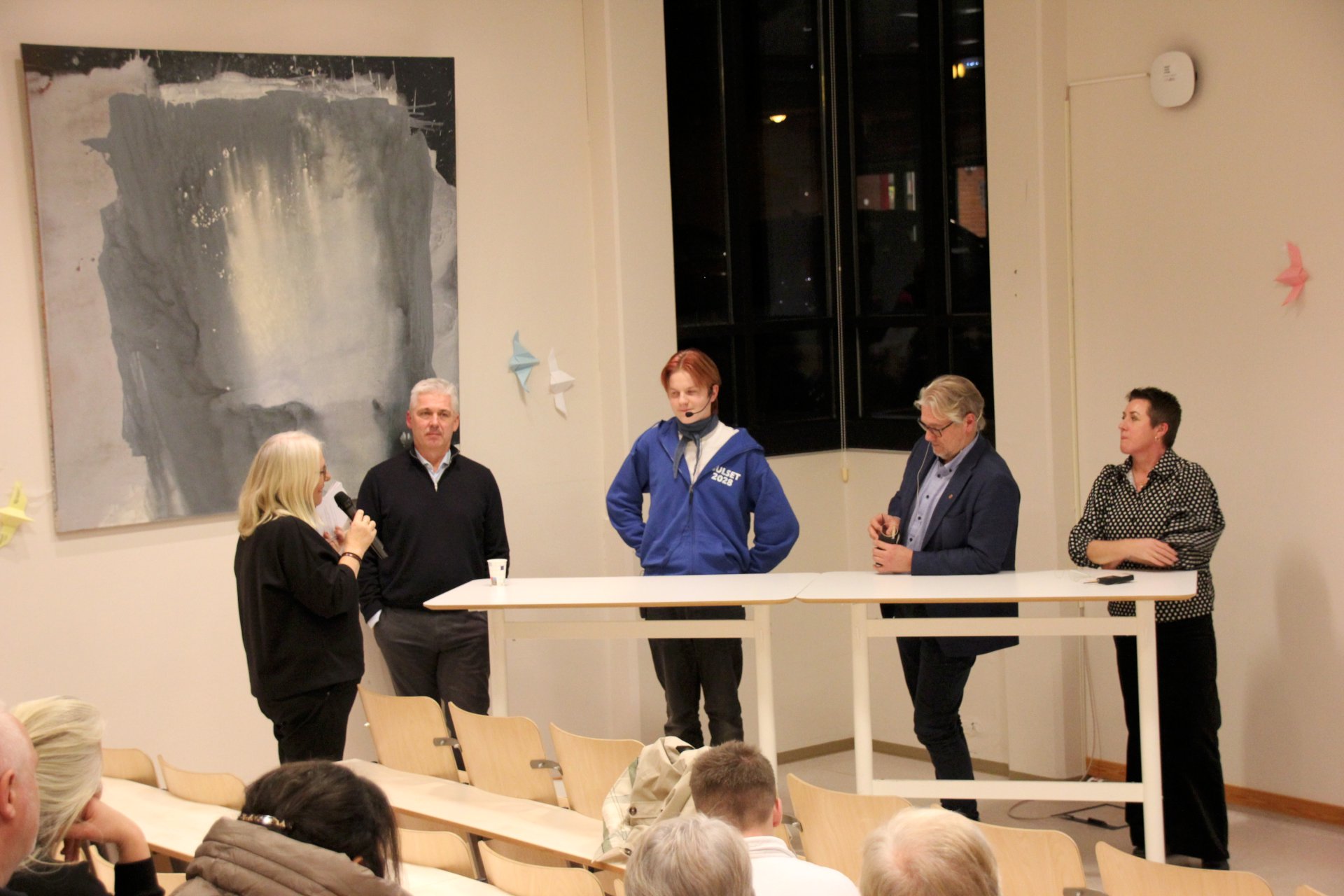 Fem personer foran publikum.