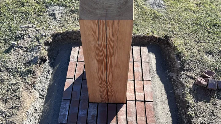 Trestolpe som står på et lite område med teglstein.