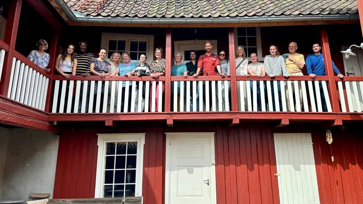Deltakerne står på svalegangen i Ibsengården og ser utover bakhagen.